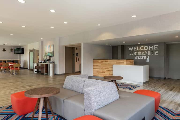 Modern hotel lobby with welcome sign, lounge seating, and front desk area