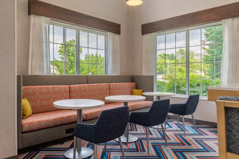 Bright lounge area with upholstered booth seating and large windows overlooking greenery