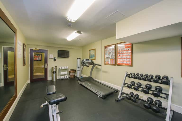 Fitness center with treadmill, exercise bike, dumbbells, and green walls