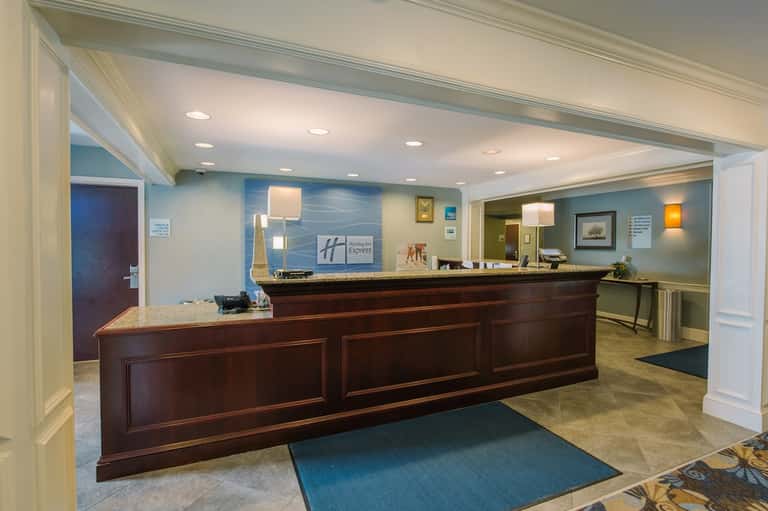 Hotel lobby with dark wood reception desk, blue walls, recessed lighting, and traditional furnishings
