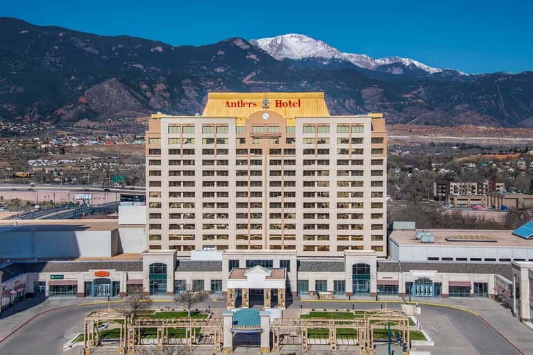 Yellow Antlers Hotel building with snow-capped mountains and town in background
