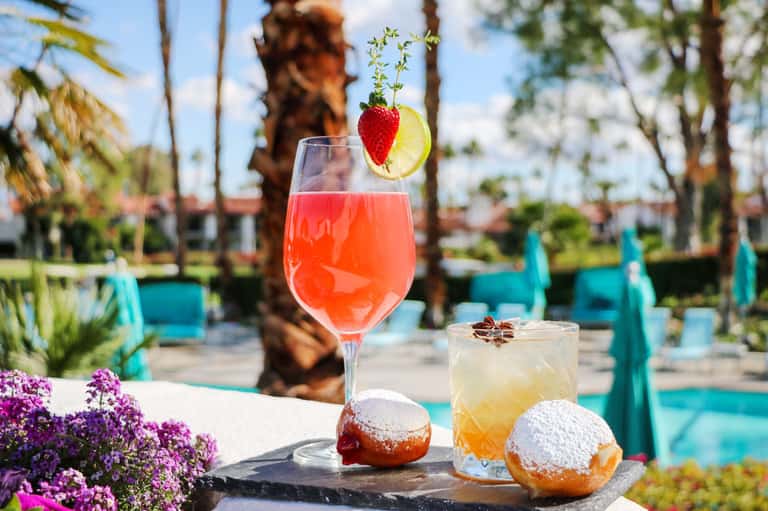 Cocktails and pastries by the pool with palm trees and turquoise lounge chairs