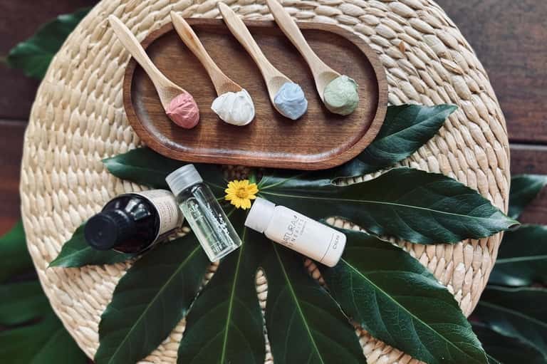 Spa products and bath salts displayed on woven tray with green leaves and flower