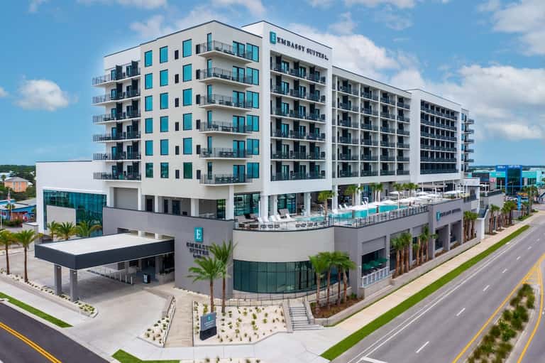 Modern beachfront resort building with turquoise accents, balconies, and ground-level pool area