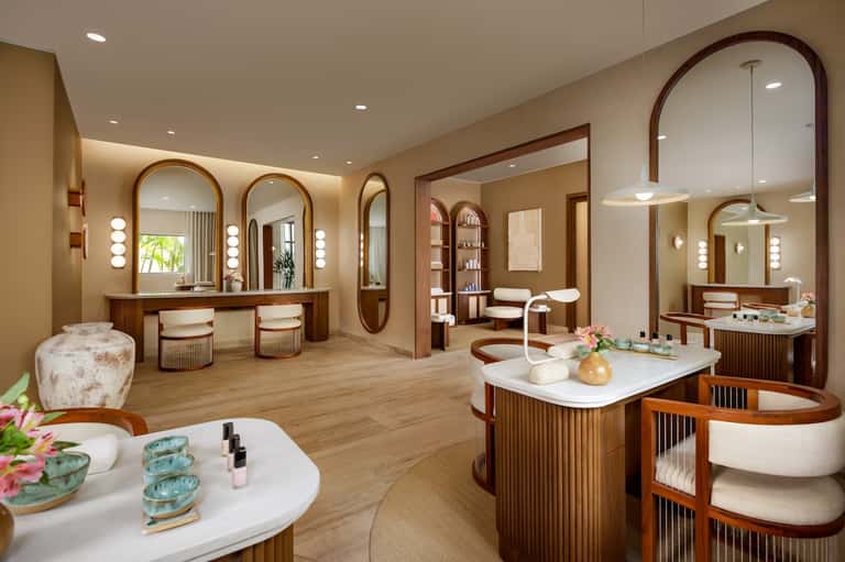 Luxurious spa suite with dual vanities, large mirrors, warm wood tones, and modern fixtures