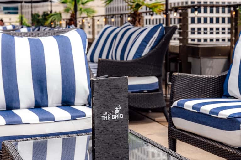 Rooftop lounge with striped navy and white cushioned chairs and urban skyline views