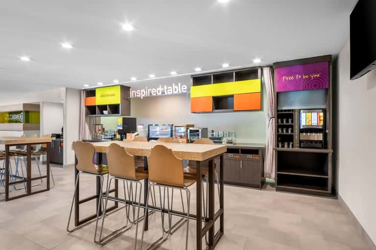 Modern hotel lobby with colorful signage, bar seating, and bright contemporary design elements