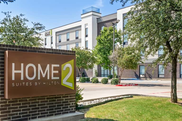 Home2 Suites by Hilton hotel building exterior with lawn and signage