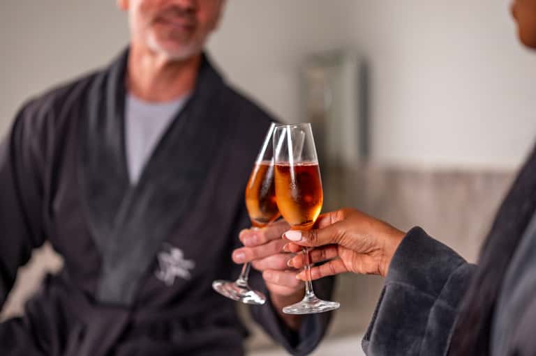 Two people clinking champagne glasses indoors during celebration