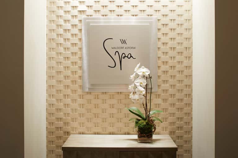 Waldorf Astoria Spa entrance sign with white orchid flower on textured wall