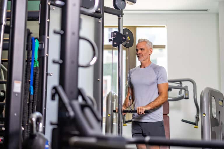 Man using weight machine equipment in bright, modern hotel fitness center