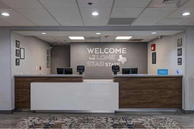 Hotel check-in desk with 'Welcome to the Lone Star State' Texas-themed wall signage