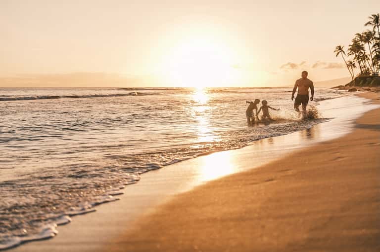 Family enjoying sunset beach swim with golden hour lighting and calm ocean waves