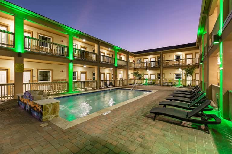 Courtyard pool with bright green architectural lighting and multi-story balconies