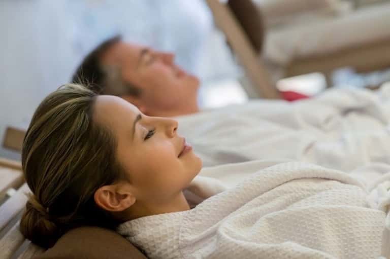 Two guests relaxing on spa beds in white linens at resort wellness center