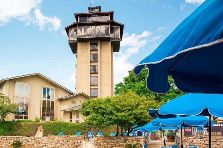 Tall observation tower next to beige building with blue umbrellas and landscaping