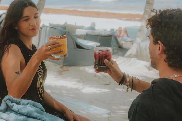 Couple toasting with cocktails on a rooftop deck overlooking a coastal harbor and boats