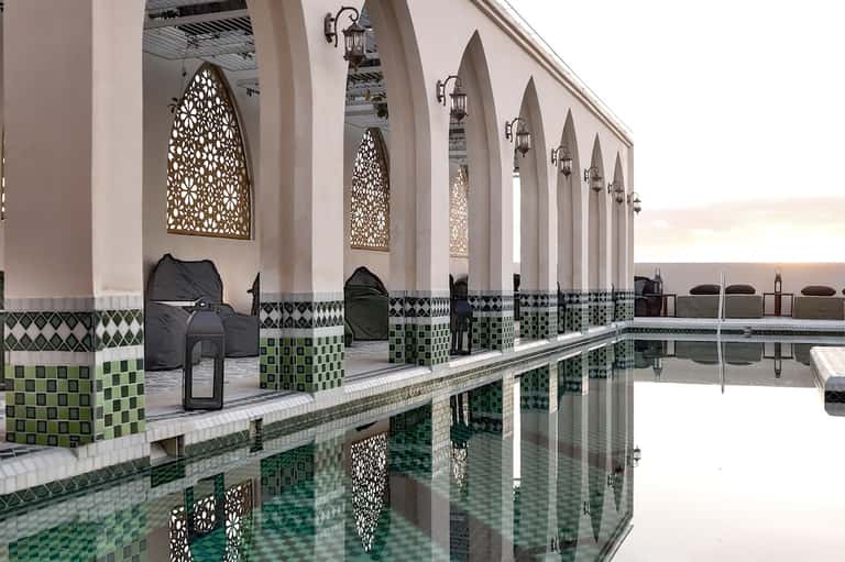 Ornate indoor spa pool with Moroccan tile work, arches, and decorative lanterns