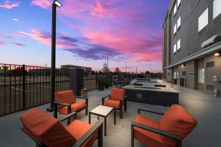 Rooftop patio with orange seating, fire pit, and sunset sky at dusk
