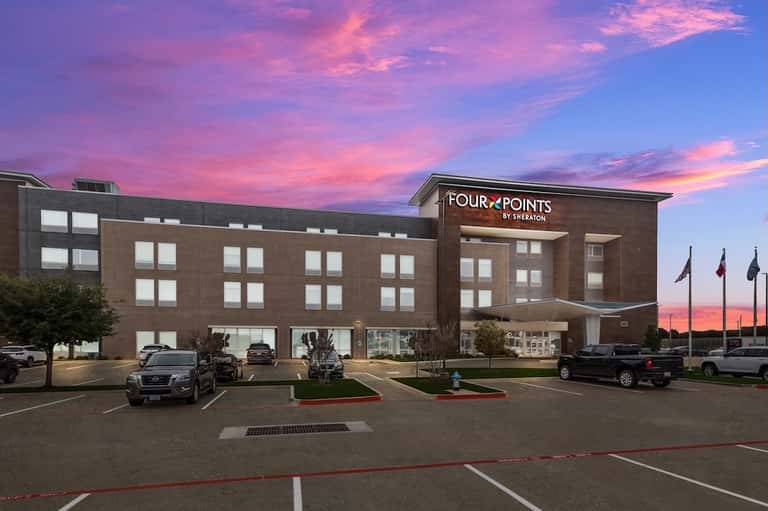 Four Points by Sheraton hotel exterior at dusk with dramatic pink and purple sky
