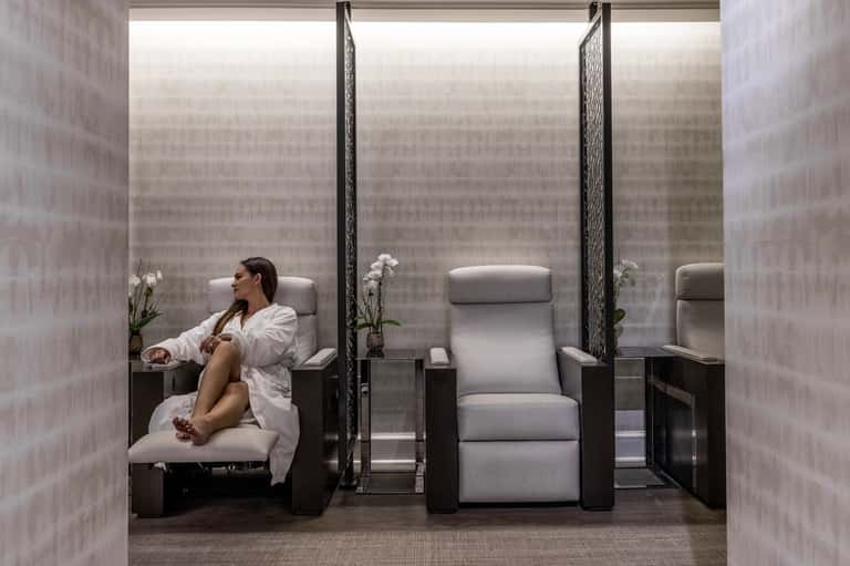 Spa relaxation lounge with recliners separated by dividers and white flowers