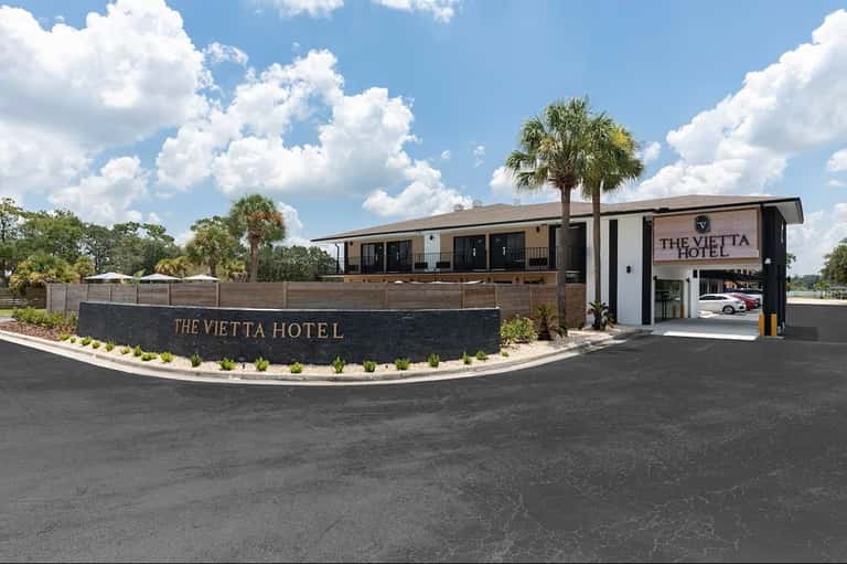 The Vietta Hotel modern exterior with palm trees, contemporary architectural design, and covered entrance