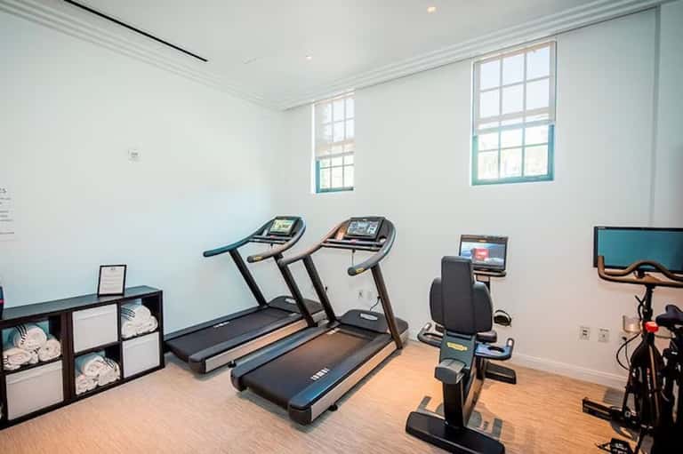 Bright fitness room with treadmills, stationary bike, and natural light from windows