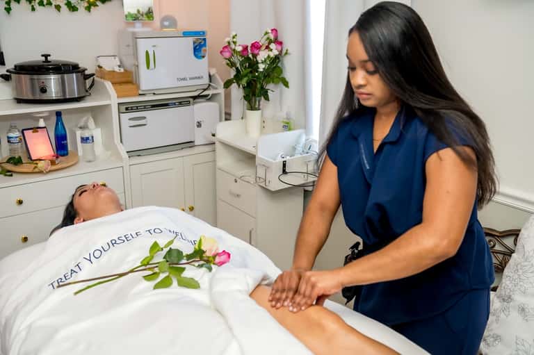 Spa therapist performing massage treatment on client in serene wellness room with flowers
