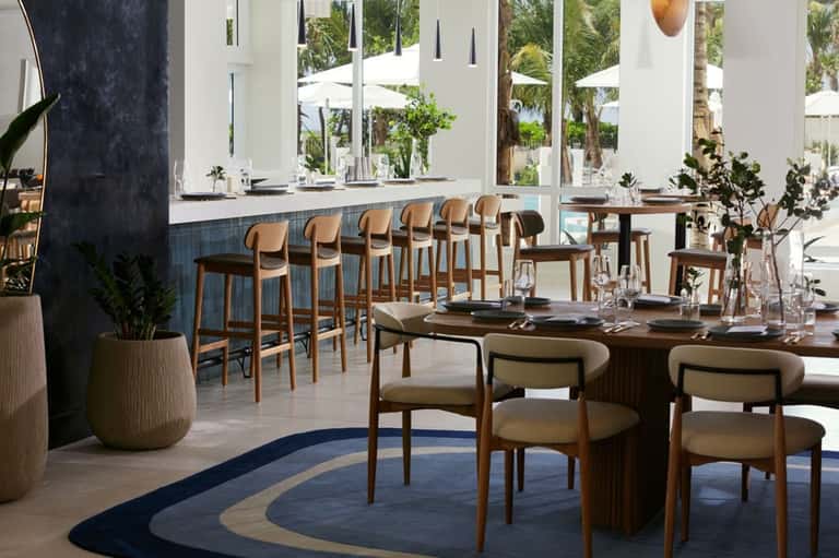 Contemporary restaurant with wooden bar seating, natural wood tables, and expansive windows