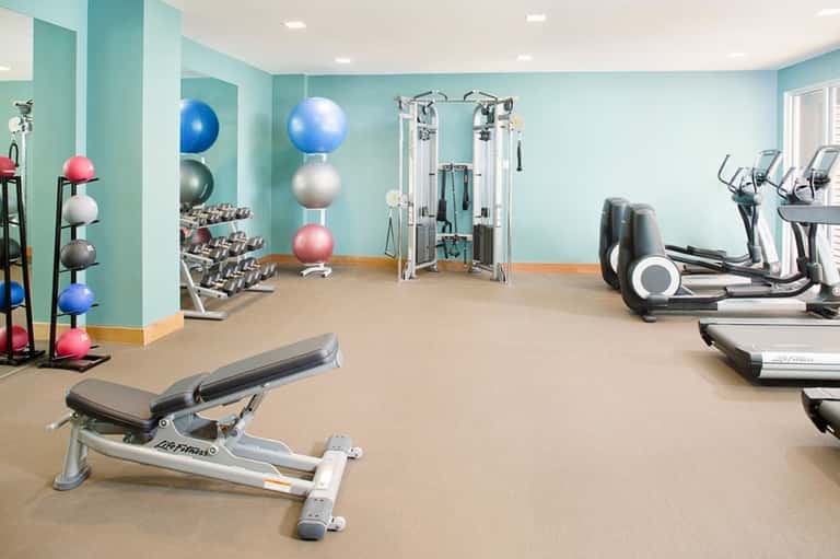 Bright fitness center with exercise equipment, dumbbells, exercise balls, and cardio machines