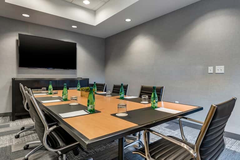 Conference room with wooden table, office chairs, TV monitor, and gray walls