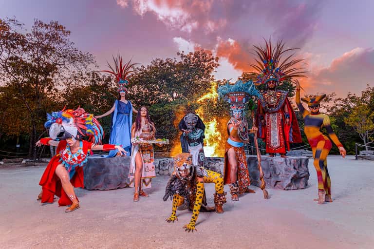 Evening entertainment show with colorful performers in elaborate costumes around fire pit