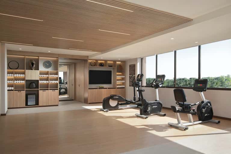Bright fitness center with exercise bikes, storage, and large windows overlooking grounds