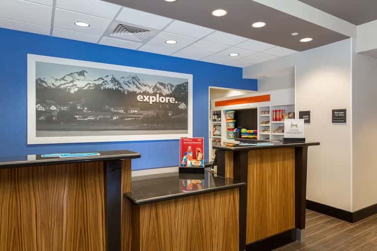 Hotel lobby front desk with blue accent wall, wooden details, and mountain landscape artwork