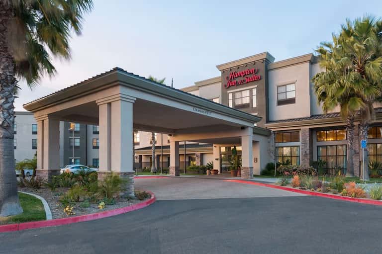 Hampton Inn hotel entrance with covered driveway, palm trees, and architectural design at dusk