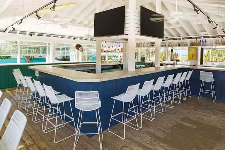 Beachfront bar with navy and white interior, high ceiling, open windows, and ocean view