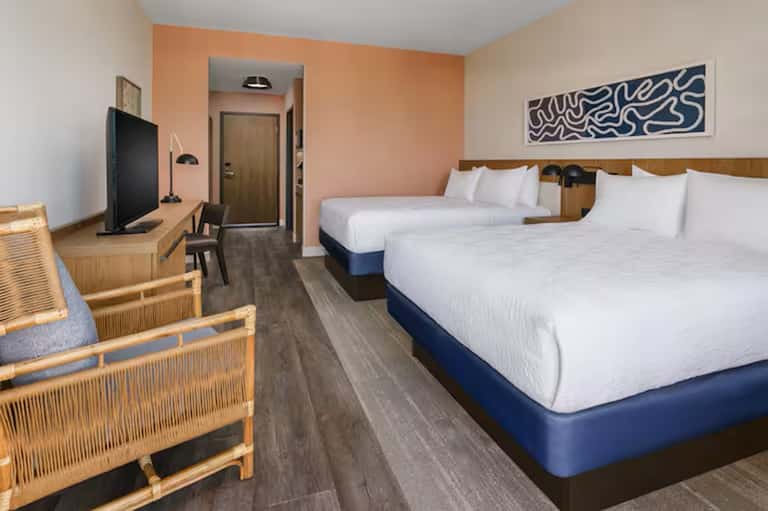 Hotel room with two queen beds, peach accent wall, and modern furnishings