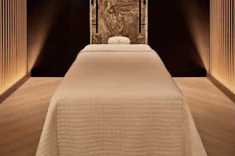 Luxury spa massage room with cream-colored table, warm lighting, and decorative wall panel