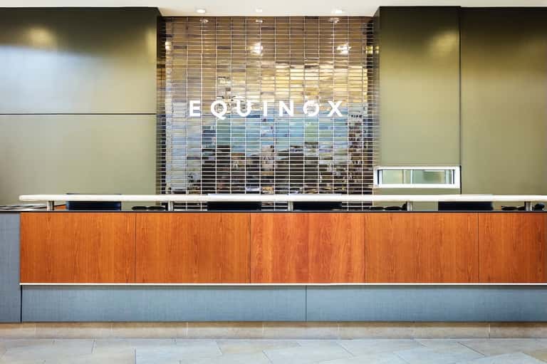 Modern hotel reception desk with wooden paneling and Equinox branding