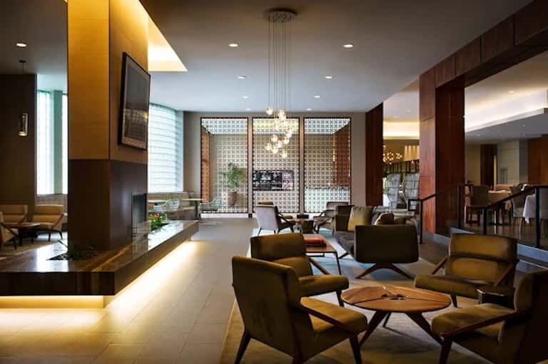 Modern hotel lobby lounge with wood accents, chairs, fireplace, and ambient lighting