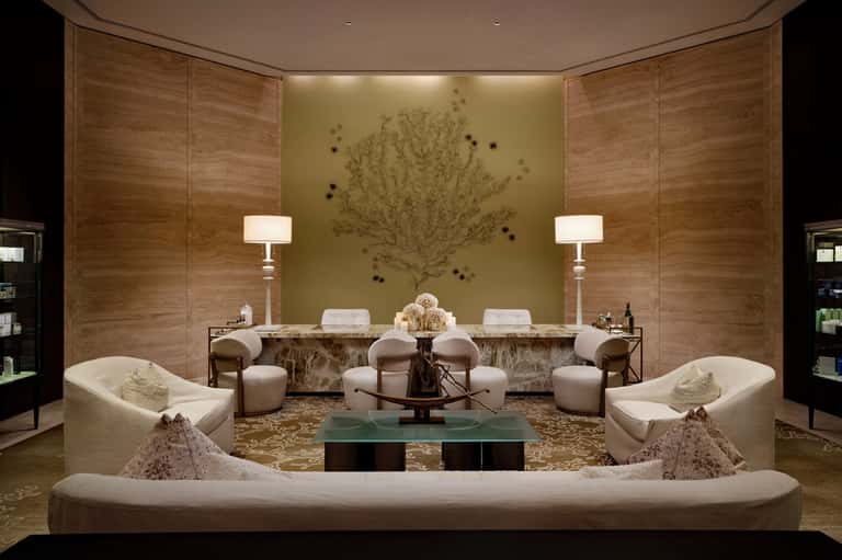 Luxury spa relaxation room with cream seating, marble counter, and nature wall art