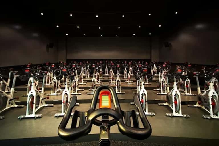 Indoor cycling studio with rows of stationary bikes and projection screen at front