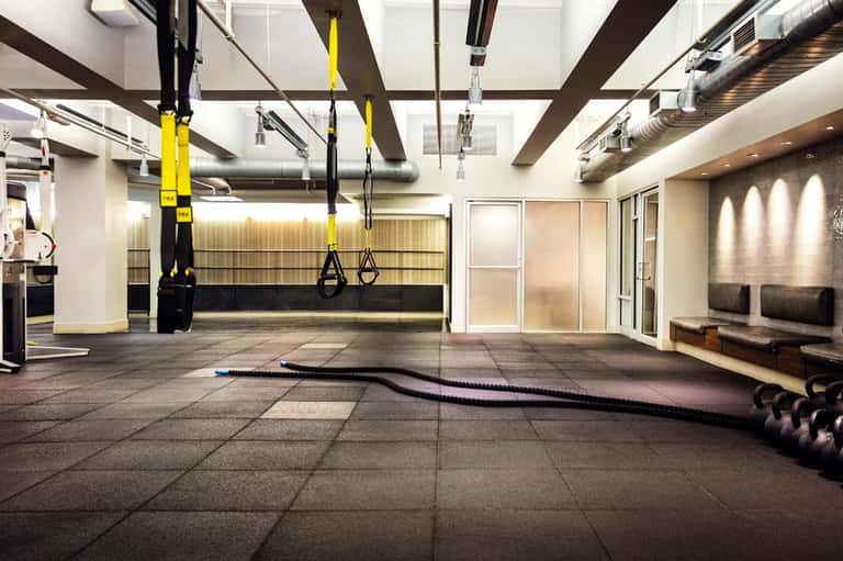 Modern fitness facility with yellow suspension equipment, mirrors, and spacious indoor training area