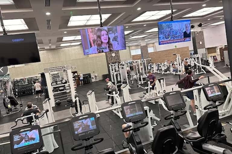 Spacious fitness facility with cardio equipment and entertainment screens