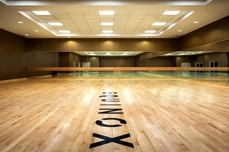 Indoor fitness center with wooden floor, mirrors, and professional workout space
