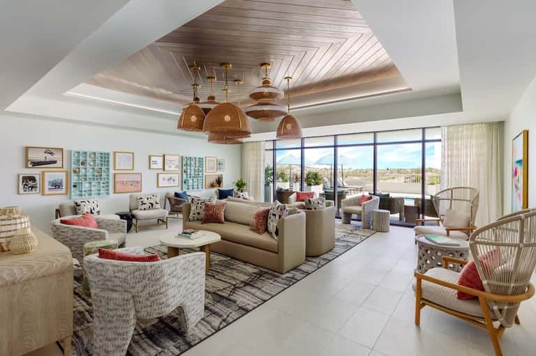 Luxurious living room with cream sofa, woven chairs, ceiling detail, and panoramic windows