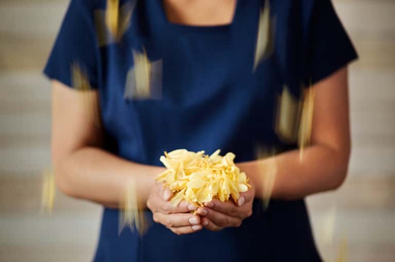 Person holding a yellow flower wearing navy blue shirt