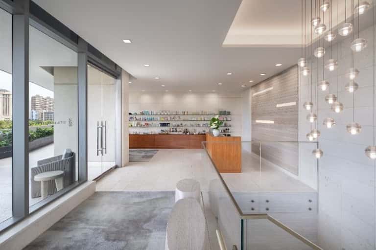 Luxury spa reception with white counters, pendant lighting, glass partitions, and modern design
