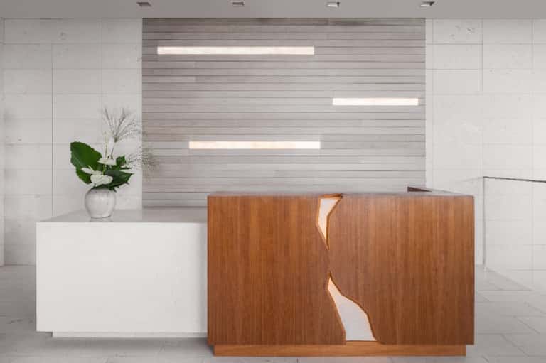 Modern hotel reception desk with wooden accent wall and minimalist design