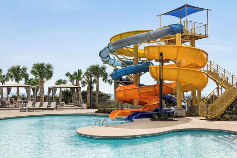 Water park with colorful spiral waterslides, lazy river pool, and palm tree landscaping